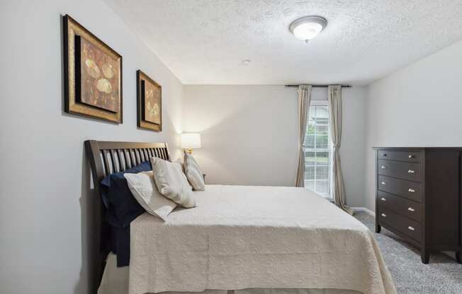 a bedroom with a bed and a dresser and a window