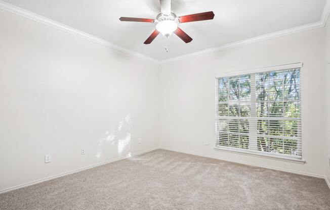 an empty living room with a ceiling fan and a window at La Ventura Apartments, Plano, 75093