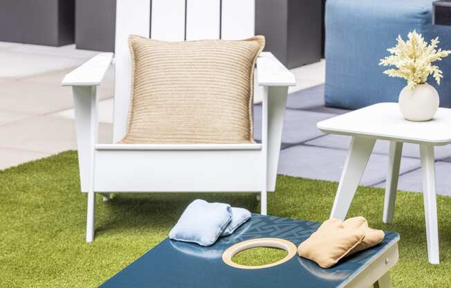 a white chair and a table with a blue rug on the grass