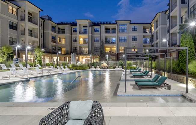 an apartment swimming pool with lounge chairs at night at The Hendrix, Georgia