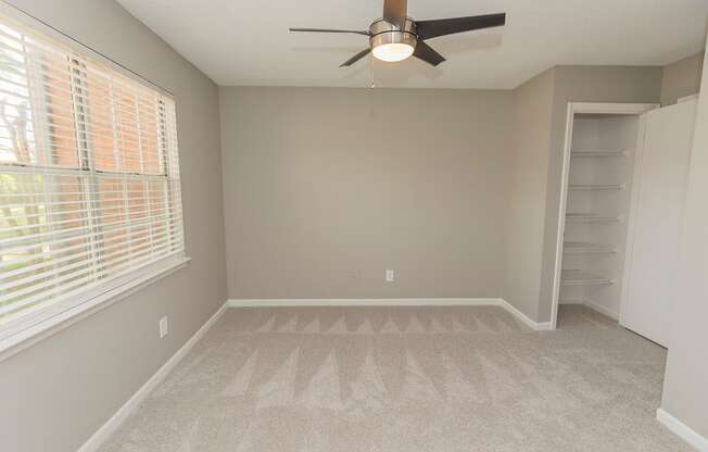 carpeted bedroom with a ceiling fan and large windows
