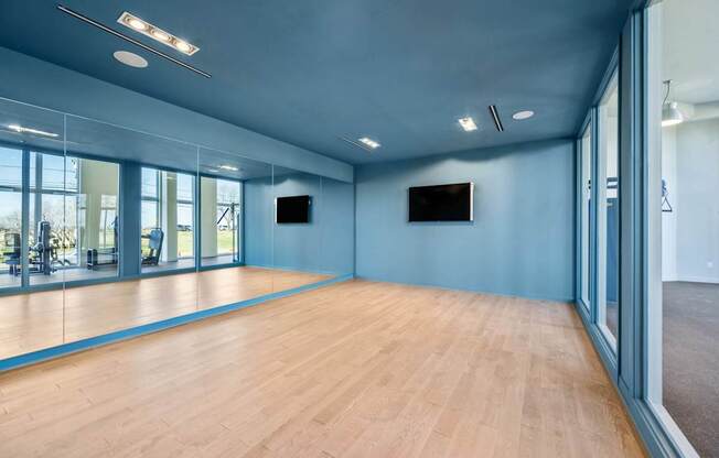 A spacious room with wooden floors and a television mounted on the wall.