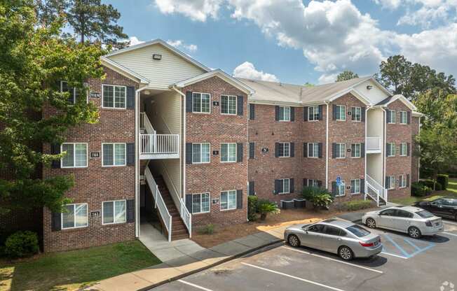 a brick apartment building with stairs and cars parked in a parking lot