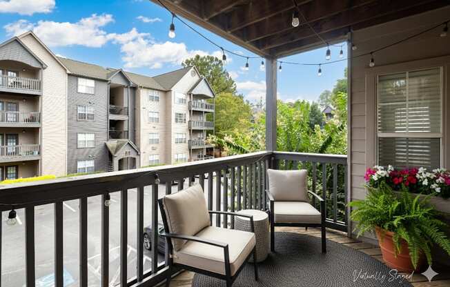 A balcony with a chair and a table with flowers on it.