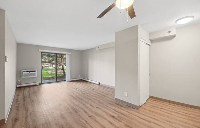 an empty living room with wood floors and a ceiling fan