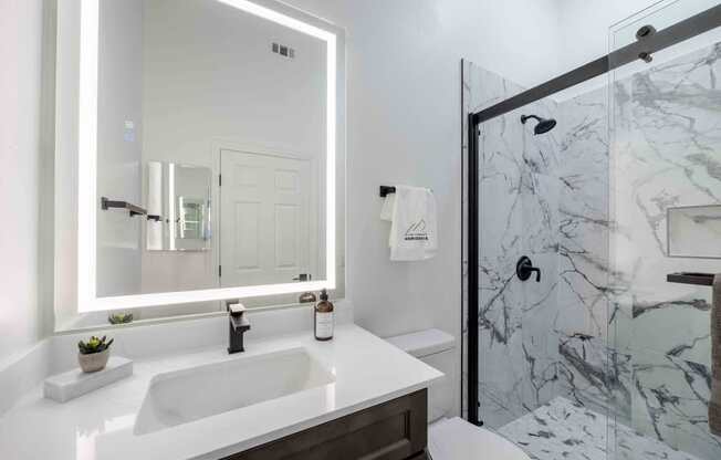 A bathroom with a marble shower and a white sink.