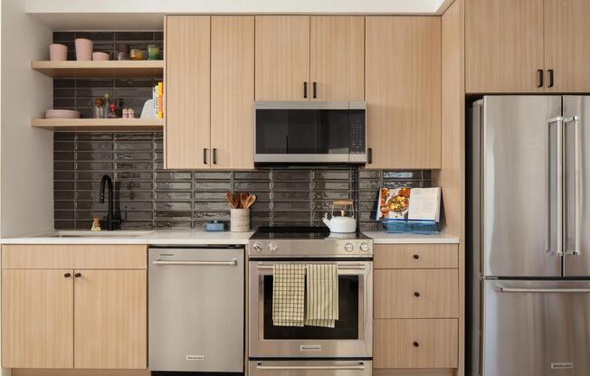 Light wood cabinetry, sleek stainless appliances, and a glossy tile backsplash create a clean, contemporary kitchen with character.