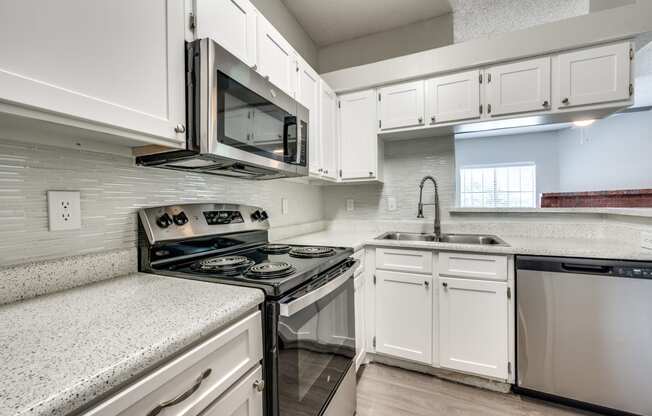 an empty kitchen with white cabinets and a stove and microwave