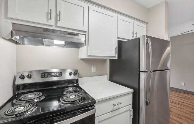 an empty kitchen with stainless steel appliances and white cabinets