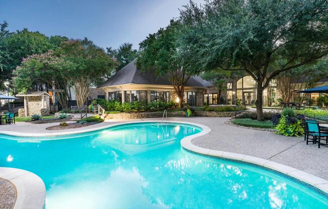A refreshing retreat awaits at the resort-style pool, surrounded by mature trees, stonework, and peaceful gathering spaces.