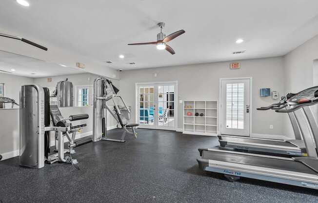 A spacious gym with a variety of equipment including treadmills, weights, and a bench press.