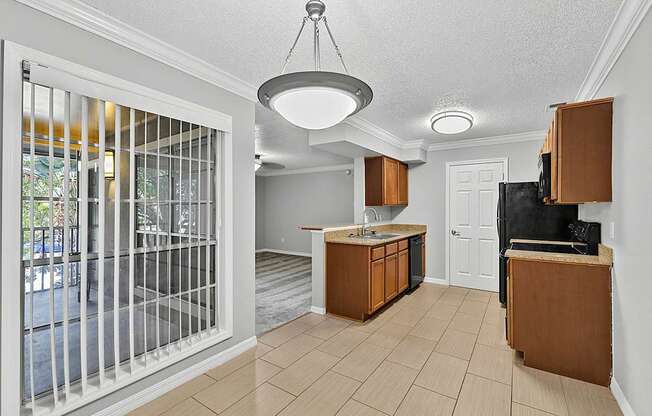 A kitchen area with a sink, cabinets, and a television.
