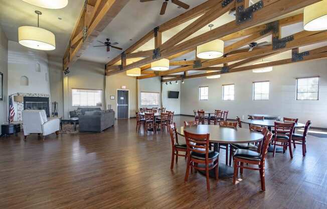 a large gathering room with tables and chairs and a fireplace