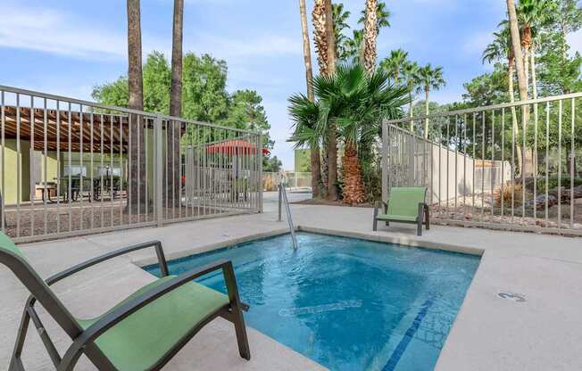 A pool surrounded by palm trees and a fence.