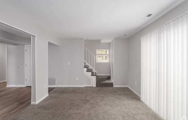 a living room with a carpeted floor and a staircase