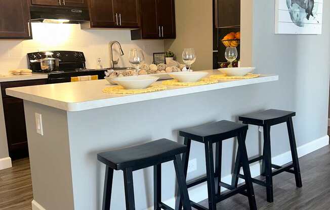 A kitchen with a white island and black stools.
