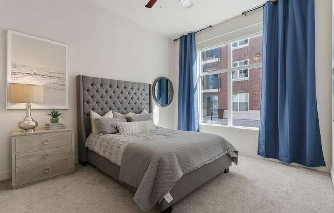 a bedroom with a bed and a window with blue curtains