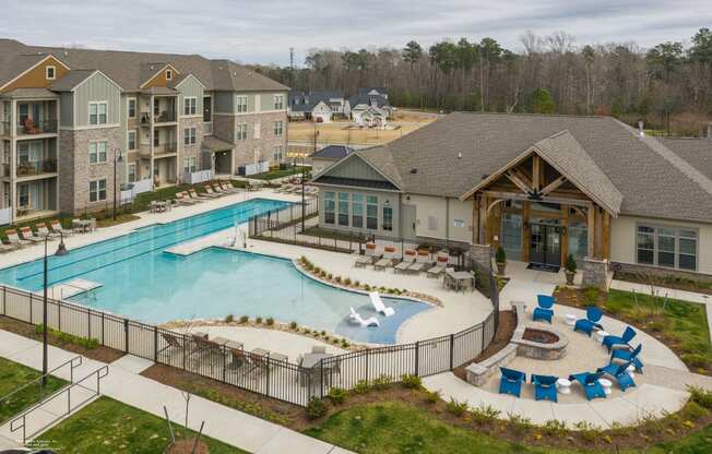 an aerial view of a resort style pool with lounge chairs and a clubhouse in the background at The Whitworth, Williamsburg, VA