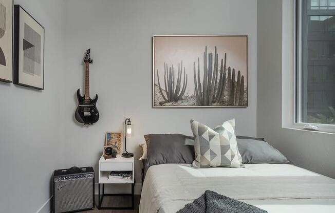 a small bedroom with a bed and a guitar on the wall