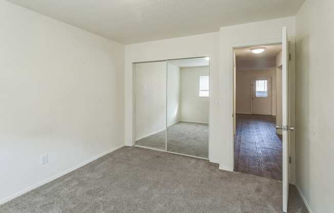 an empty living room and hallway with a door to a closet