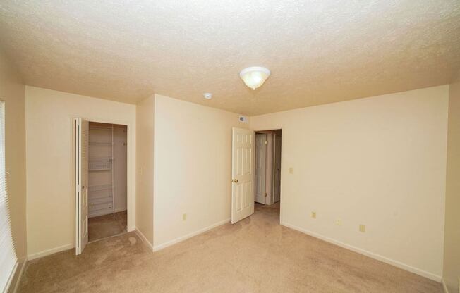 A bedroom with a walk in closet and plush carpet at Foxwood and The Hermitage, Portage, MI