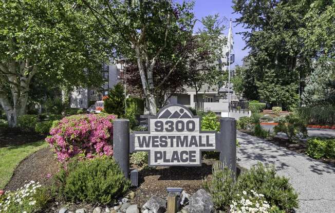 Property Sign with Address surrounded by flowers and trees in the background at West Mall Place Apartment Homes, Everett, Washington
