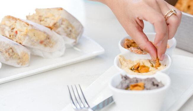 a person putting food on a plate on a table