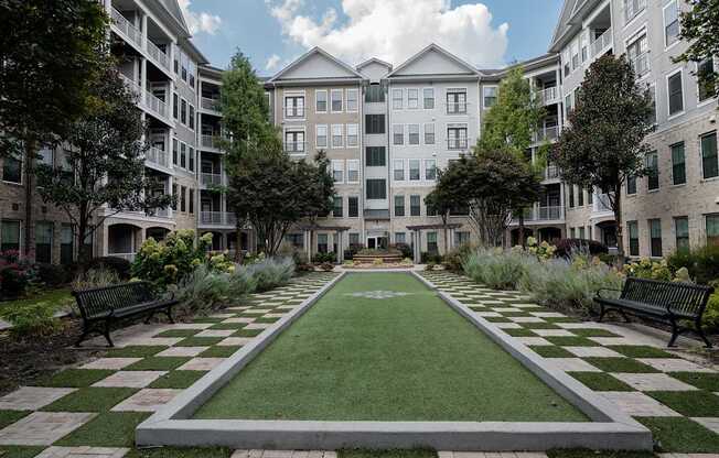A courtyard with a green lawn and a checkerboard pattern of grass and concrete.