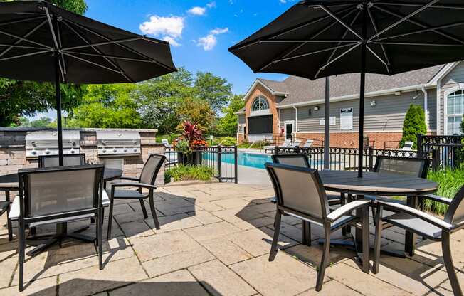 a patio with tables and umbrellas next to a swimming pool