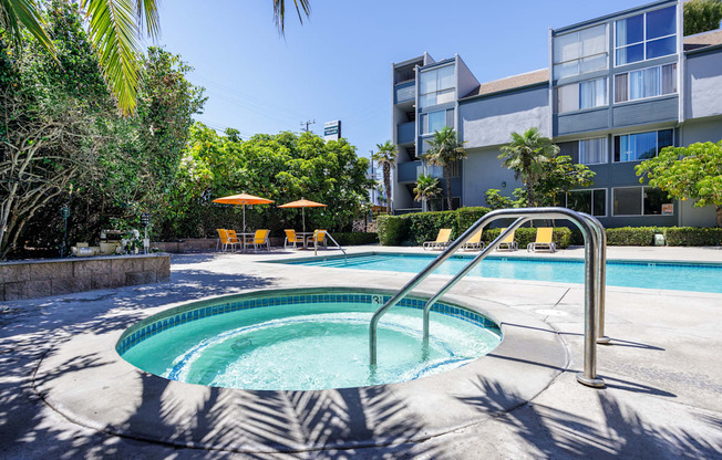 a hot tub in a pool with an apartment building in the background