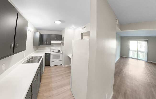 an empty kitchen and living room with white counter tops and wood floors