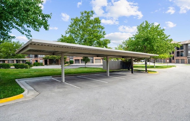 A parking lot with a covered parking area and trees in the background. at Crescent Apartment Homes, Lenexa, 66219