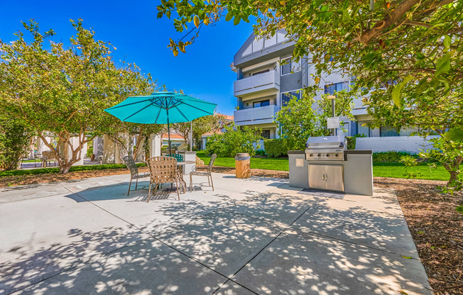 a patio with a grill and umbrella