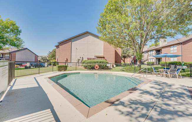 A small pool in a courtyard surrounded by chairs and trees.