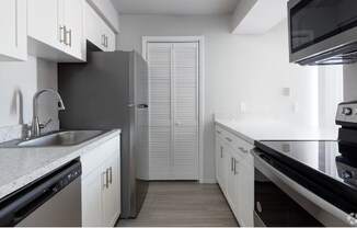 a kitchen with white cabinets and a stainless steel refrigerator at Southern Oaks Residences
