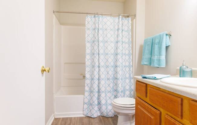 a bathroom with a white toilet next to a shower with a blue shower curtain