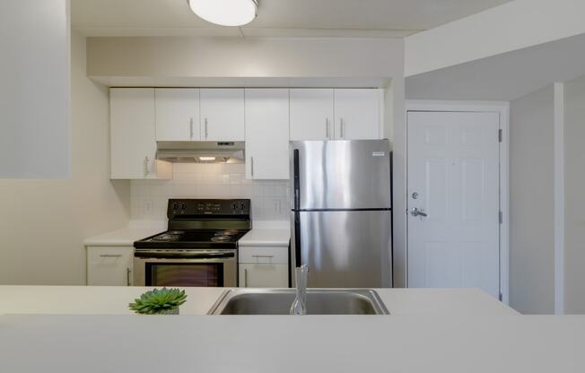 a kitchen with white counters and a stainless steel refrigerator