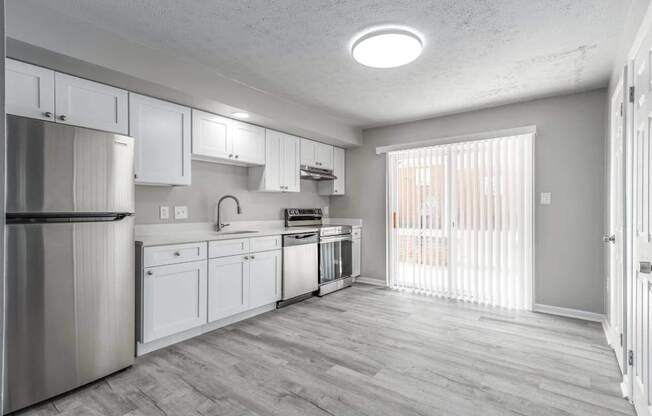 A kitchen with white cabinets and a stainless steel refrigerator.