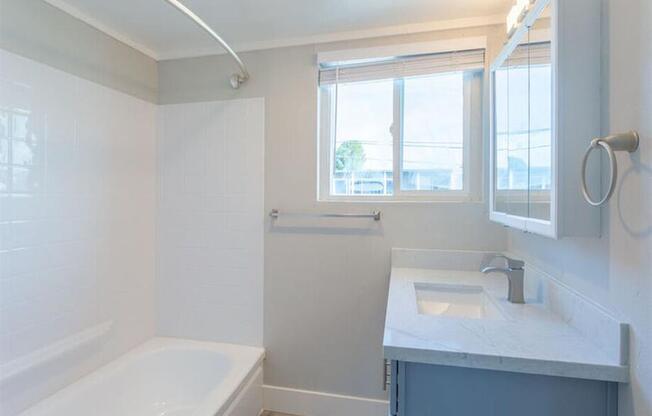 a white bathroom with a tub and a sink and a window at The Preston at Hillsdale, California