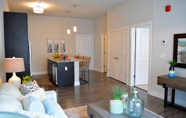 A living room with a white couch and a coffee table with a bottle on it.