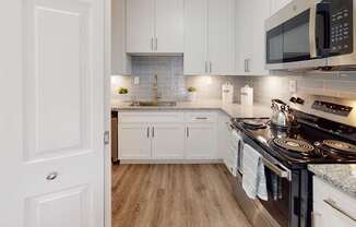 A modern kitchen with white cabinets and a black stove top.