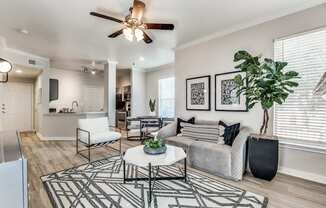 A living room with a white couch, a black and white rug, and a ceiling fan.