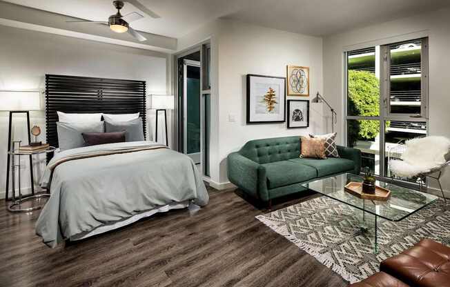 A bedroom with a bed, a green couch, and a glass table.