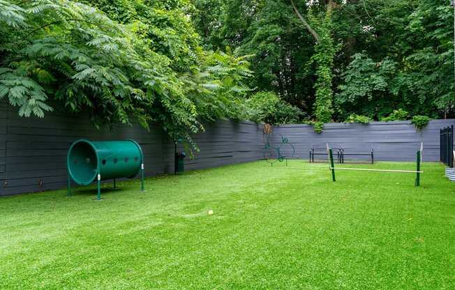 A green pipe sits on a lawn next to a wall.