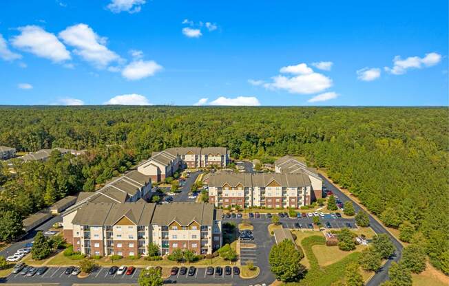 an aerial view of an apartment complex with trees and a blue sky
