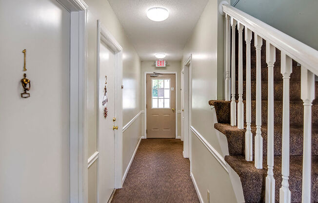 the hallway of a house with a staircase and a door to a room