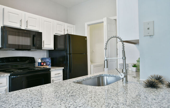 A kitchen with black appliances and white cabinets.at Braxton Woods Lake, Greenville, 29607