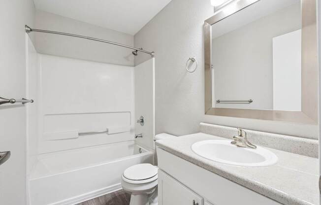 A white bathroom with a toilet, sink, and shower.