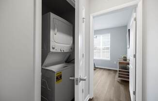 A small room with a white fridge and a door open to a hallway.