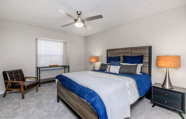 A bedroom with a bed, chair, and lamp.